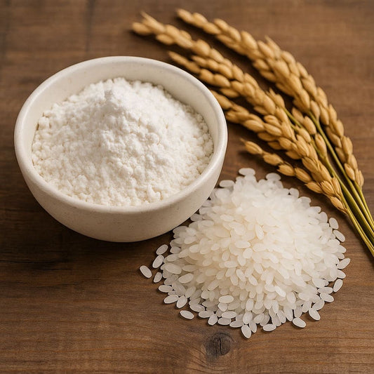 木のテーブルの上に置かれた丸い白い器に盛られた米粉と、横に並ぶ生米と稲穂の写真