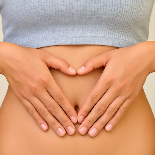 クロップトップを着た女性が、お腹に両手を重ねて優しく添えている様子